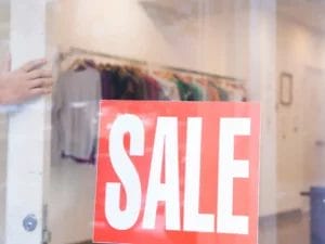 a red and white sign in a shop window that says "sale" on it