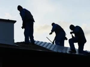 three people are working on the roof of a building