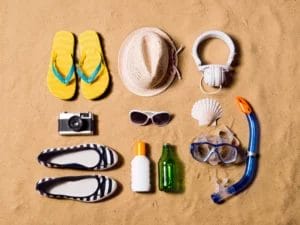 multiple beach accessories are laid out on a sandy beach