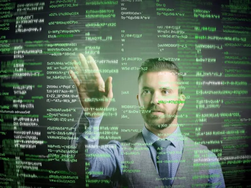 a man is standing in front of a computer screen with lots of green text