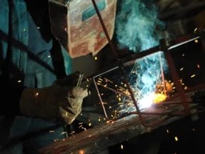 a man is welding a piece of metal with a welding mask on