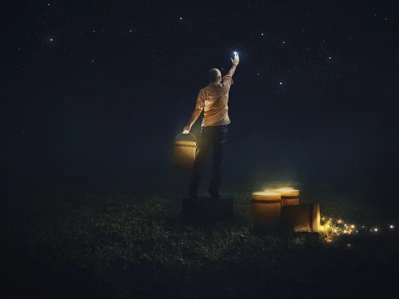 a man is standing in the dark holding a light in his hand .