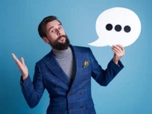 a man in a suit is holding a speech bubble with three dots on it