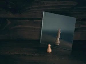 a wooden chess piece is reflected in a mirror on a wooden table .