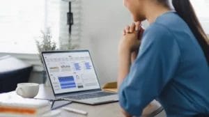 a lady looking a the screen of a laptop showing reports through graphs