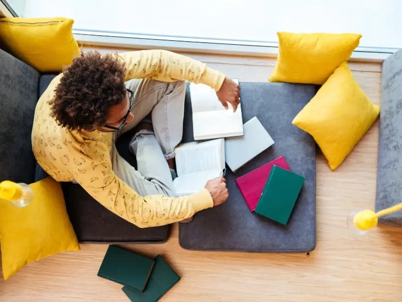 man sitting down and reading books