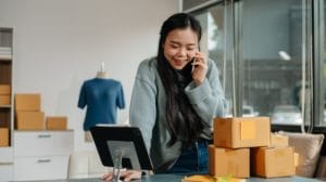 a small business owner talking on the phone with a tablet and boxes in front of her