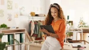 a lady inside a small business shop is sitting on a table and using a tablet